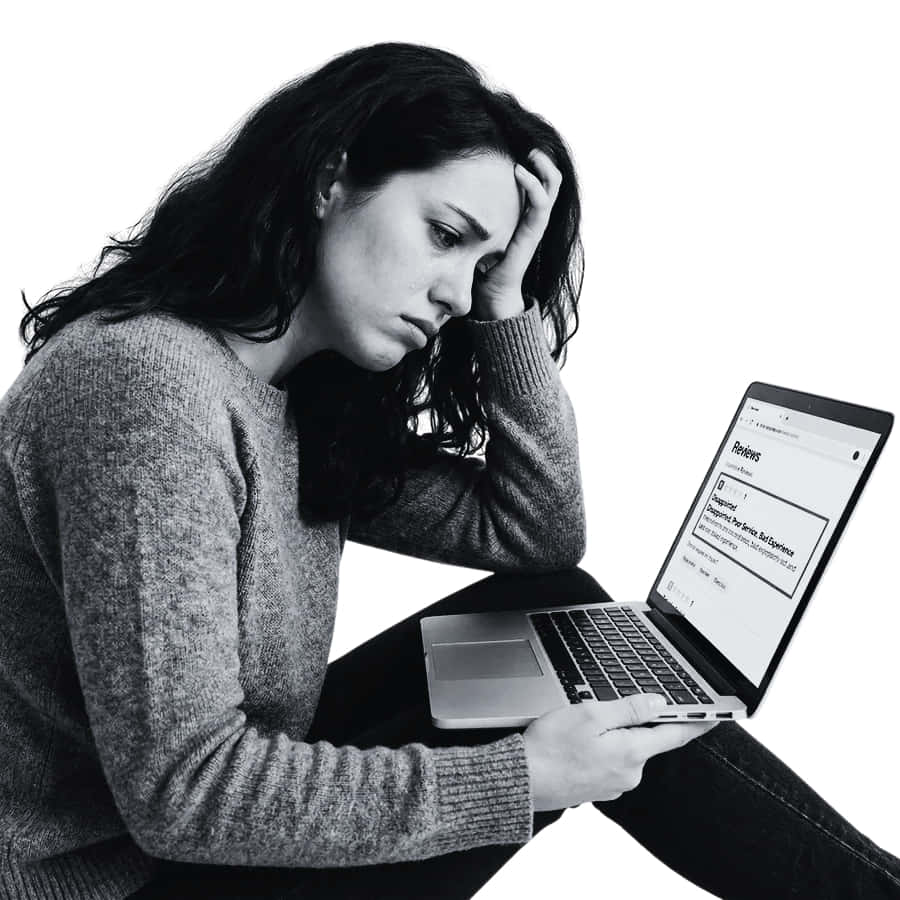 Una donna con lunghi capelli scuri siede tenendo la testa in una mano, con aria stressata, mentre utilizza un computer portatile. Sullo schermo del portatile appare una pagina con la scritta "Rifiuto".